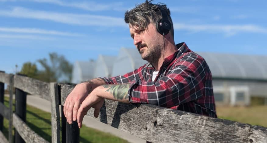 man by fence with headphones on