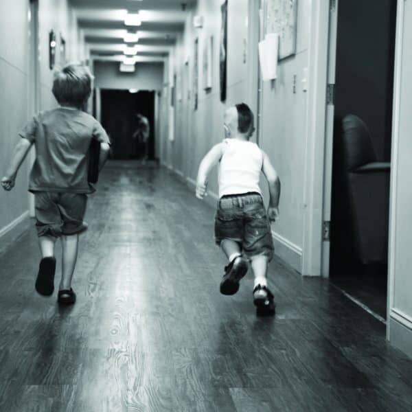 two young boys running down the shelter hallway