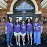 five staff members wearing purple shirts in front of the shelter