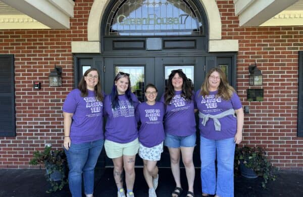 five staff members wearing purple shirts in front of the shelter
