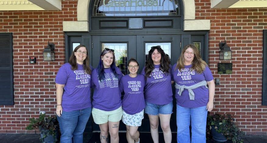 five staff members wearing purple shirts in front of the shelter