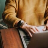 person in yellow sweater on laptop