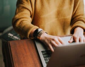 person in yellow sweater on laptop