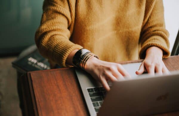 person in yellow sweater on laptop