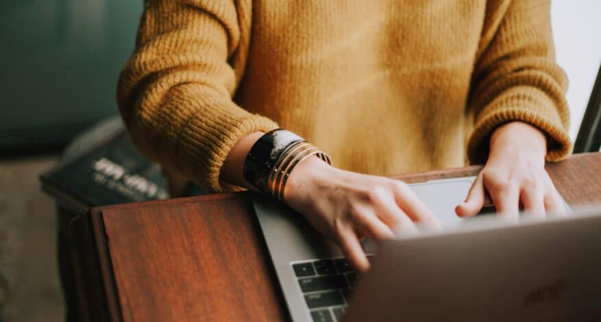 person in yellow sweater on laptop
